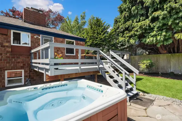 The fully fenced backyard with large deck, slate patio and hot tub!