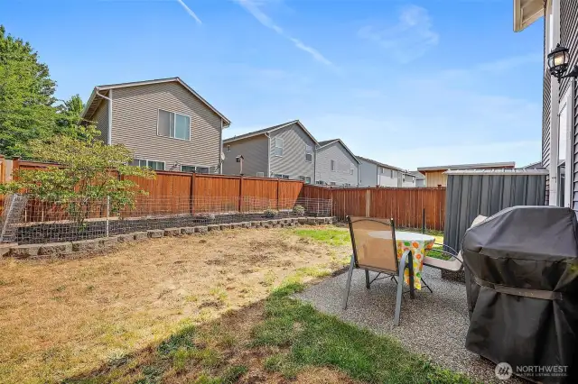 Fully fenced back yard with patio and raised garden.
