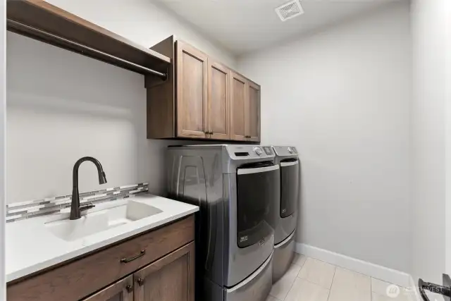 Main floor laundry room with sink and built in cabinetry