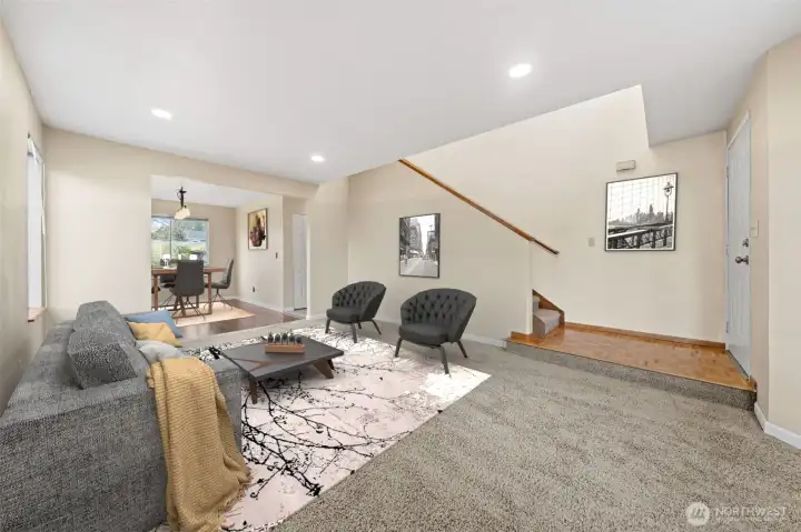 Bright and welcoming, this spacious living room features plush carpet, neutral tones, and recessed lighting for a warm, inviting ambiance. The open layout seamlessly connects to the dining area, creating a perfect flow for entertaining or relaxing.
