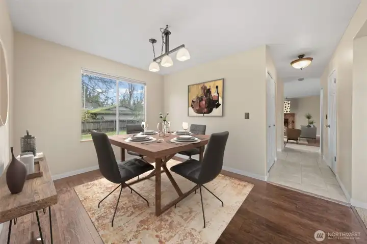 The dining room offers a comfortable setting with large windows that frame backyard views and fill the space with natural light. Its open connection to both the living and family rooms makes it ideal for gatherings. Notice the updated laminate flooring.