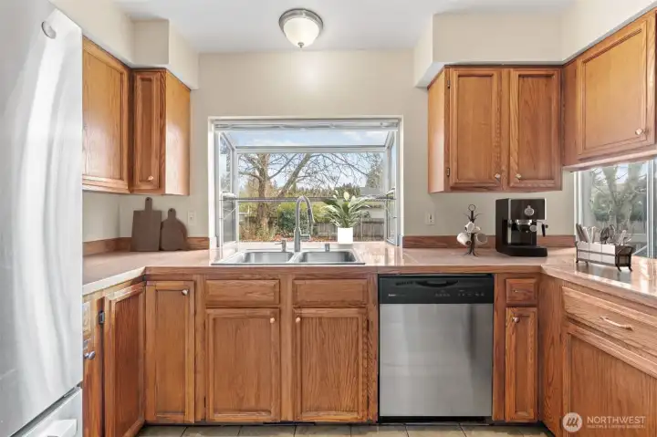 Enjoy a sunlit kitchen with a wide garden window and dual sinks, ideal for cooking and entertaining. Warm wood tones and plenty of cabinetry create a timeless and inviting space for everyday living.