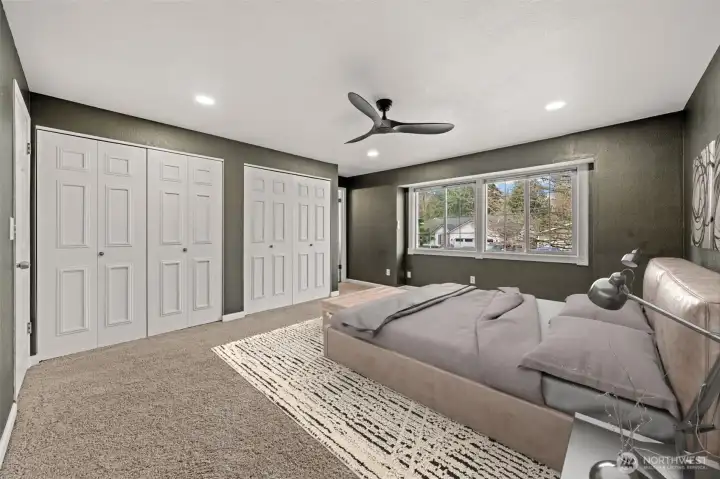The spacious Primary Suite offers plush carpeting, recessed lighting, and a large window that frames peaceful neighborhood views. Dual closets provide generous storage while maintaining a clean, modern aesthetic.