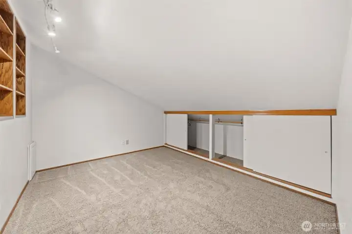 This versatile loft area offers built-in shelving and extra storage behind sliding doors, making it perfect for organization or creative use. Soft carpeting and recessed lighting enhance the comfort and functionality of this unique space.