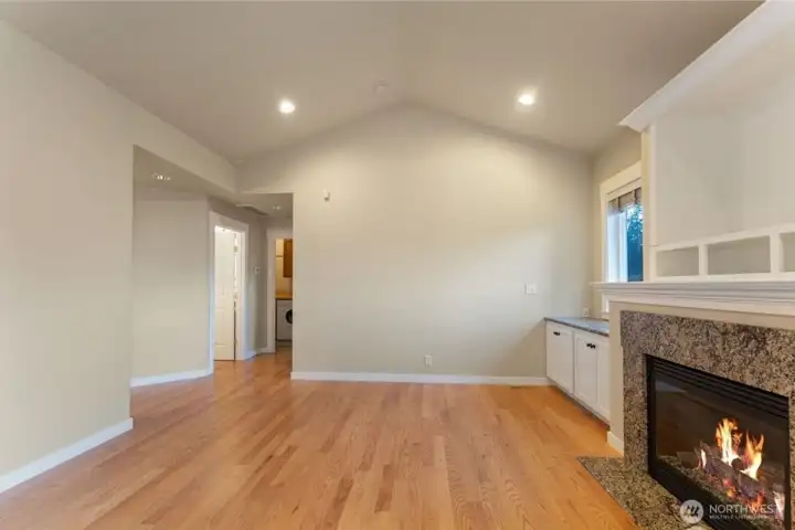 Alternate view of the living room showing the hallway that leads to the main-floor powder bath and primary bedroom, highlighting the convenient main-level living layout. Photo depicts the room without furniture; seller furnishings are currently in the home.