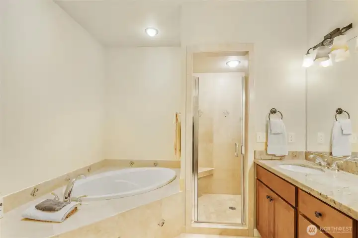 Spacious five-piece primary bathroom with soaking tub, walk-in travertine tile shower, and dual sinks.