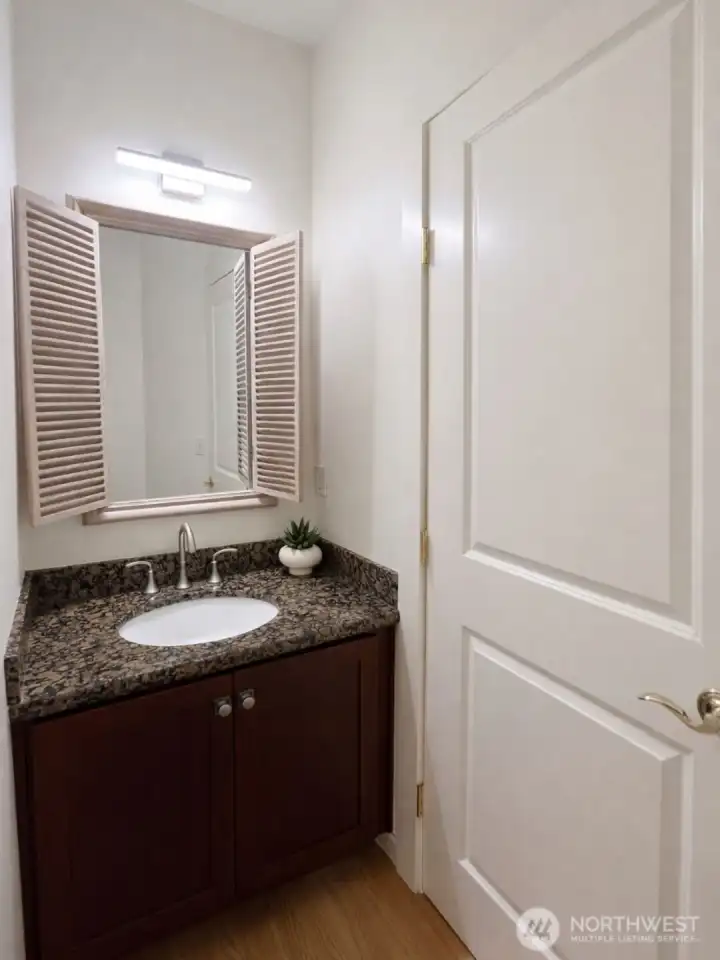 main floor primary bathroom with charming mirror, granite counter and new modern lighting.