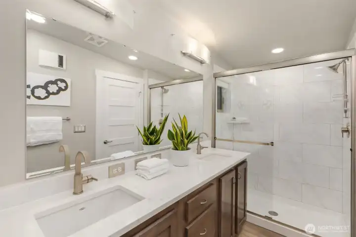 Thoughtfully finished with quartz counters, warm cabinetry, and a spacious glass-enclosed shower, the secondary bath balances function with understated style. Thoughtfully finished with quartz counters, warm cabinetry, and a spacious glass-enclosed shower, the secondary bath balances function with understated style.