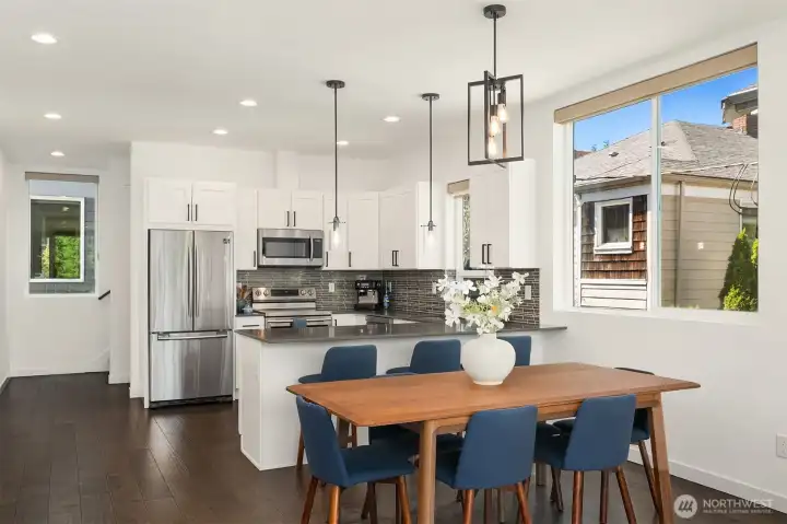 Open main level with defined dining space, modern kitchen, wide-plank flooring, and a wider townhouse floor plan for gathering.