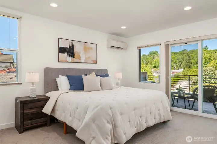 Upper-level primary suite with cozy carpeted floors, large windows, private separation from the lower bedrooms, and direct balcony access nearby.