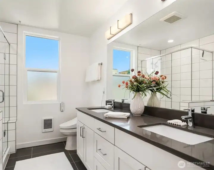 Primary ensuite bathroom with dual-sink vanity, modern cabinetry, framed mirrors, tile flooring, and contemporary finishes.