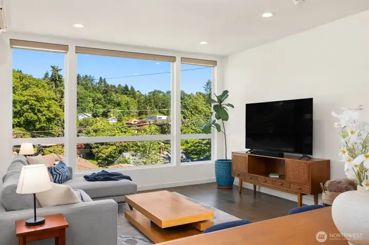 Additional living room angle showing the wider main-floor layout, large windows, and flexible furniture placement.