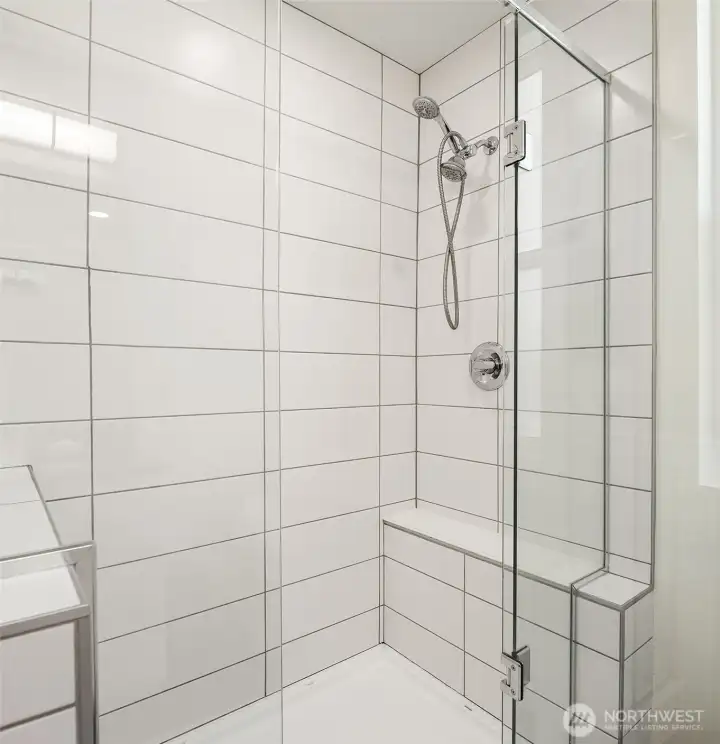 Large tiled shower with glass enclosure, modern plumbing fixtures, and clean contemporary bathroom finishes.