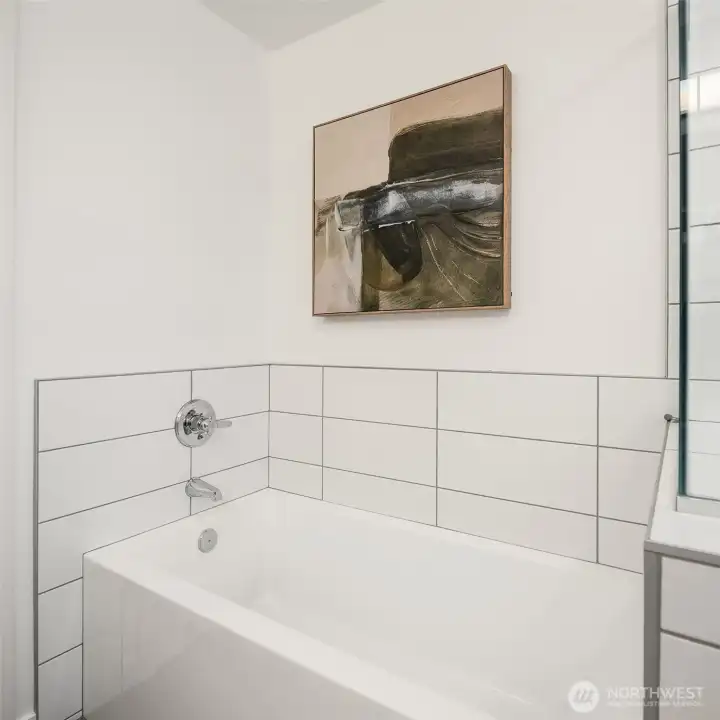 Primary bath soaking tub with tile surround, modern fixtures, and window placement for natural light.