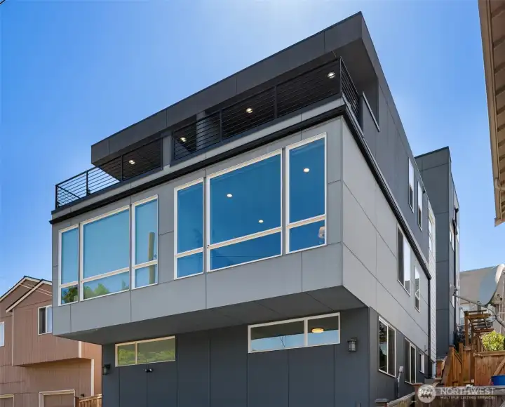 Side-angle exterior view showing the attached/zero-lot-line townhouse design, modern flat-roof profile, vertical siding, and multi-level window placement.