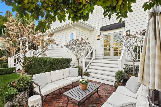 French doors lead to back deck constructed with durable composite decking with well-maintained painted railings and backyard patios made from reclaimed brick original to the home.