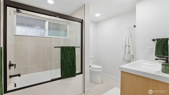 Bright and modern secondary bathroom featuring a sleek tub/shower combo with updated tile & ample storage.