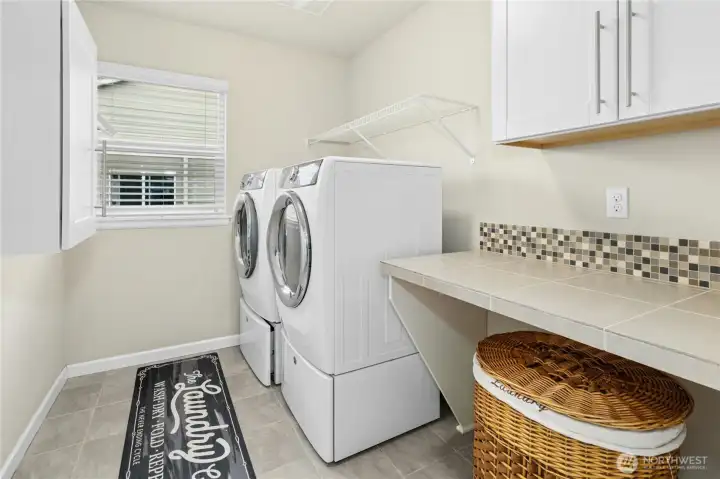 Upper level laundry room with folding counter and cabinets.