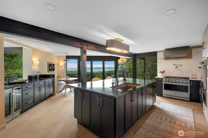 Chef's kitchen with 10' granite island, wet bar, and folding glass door leading to patio