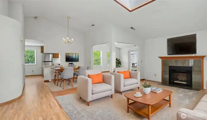 Great room and dining area feature an open-concept floor plan with a skylight and cozy fireplace.