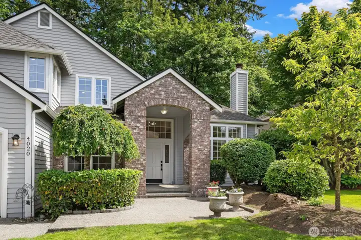 A grand stone-accented entryway framed by mature trees and manicured landscaping sets an elegant first impression, hinting at the quality upgrades and thoughtful design waiting inside.