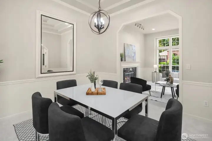 The dining room's crisp white walls, tray ceiling details, and sophisticated chandelier come together to create a polished, magazine-worthy space that feels both timeless and thoroughly modern.