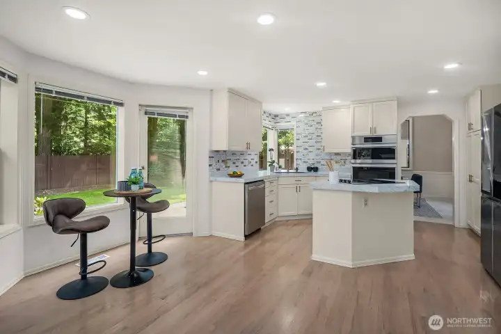The updated kitchen opens beautifully to the main living areas, featuring a large island with bar seating, premium smart appliances, and rich hardwood floors that carry the home's elevated style seamlessly from room to room.