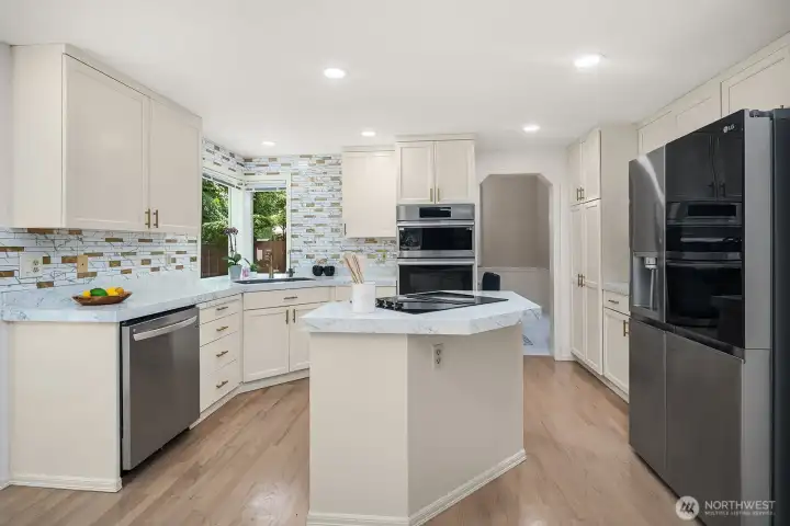 A closer look at the kitchen reveals crisp white cabinetry, a classic tile backsplash, and a full suite of high-end smart appliances that make this space as functional as it is beautiful.
