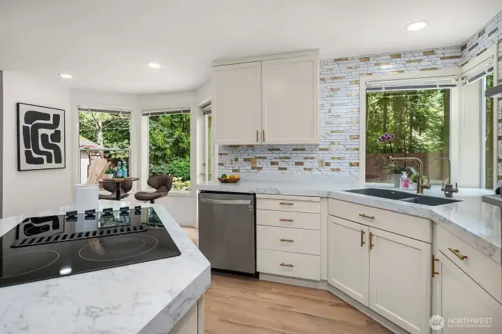 Wraparound windows above the sink frame a beautiful view of the surrounding greenery, flooding the kitchen with natural light and bringing the tranquility of the backyard setting right into the heart of the home.