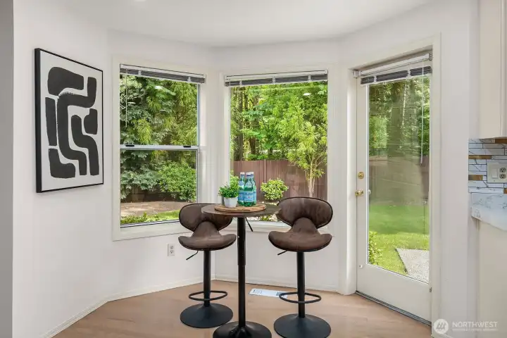 A sunny breakfast nook with French doors opening directly to the backyard creates a seamless indoor-outdoor connection, offering a bright and casual spot for morning coffee with a serene greenbelt backdrop.