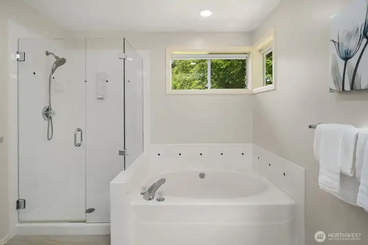 A closer look at the ensuite highlights the oversized jetted soaking tub and frameless glass shower, with a window bringing in soft natural light to complete the serene, spa-inspired atmosphere.