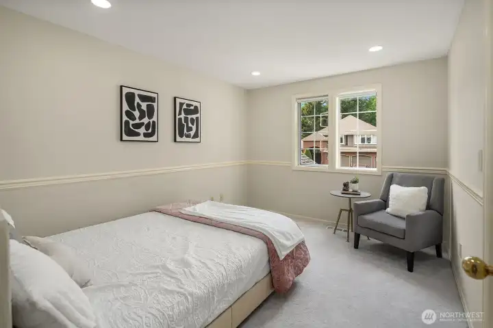 A well-proportioned secondary bedroom with soft neutral tones, plush new carpeting, and a bright window offers a comfortable and flexible space for guests, family, or a dedicated hobby room.