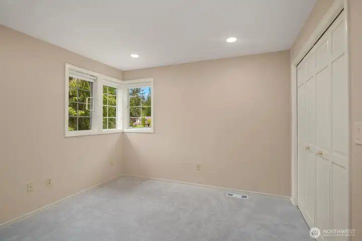 A third secondary bedroom with plush carpeting, recessed lighting, and a bright window provides flexible space that works equally well as a bedroom, home office, or creative studio.