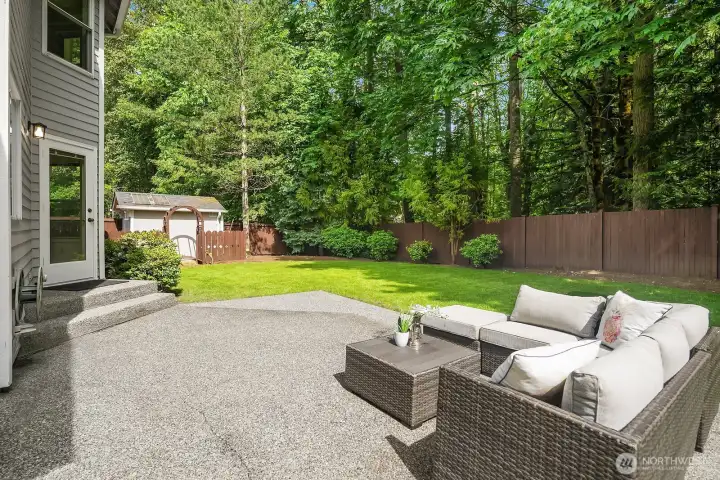 The expansive patio provides ample room for outdoor furniture and al fresco entertaining, with the fully fenced yard and towering greenbelt trees creating a private, park-like setting just steps from the back door.