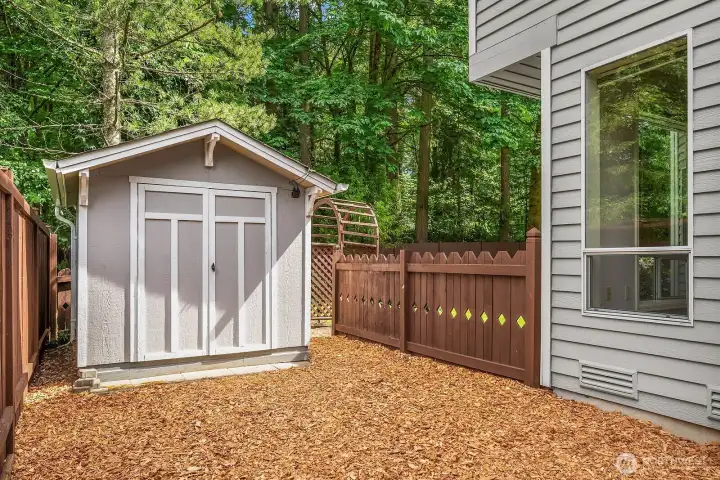 A well-placed storage outbuilding tucked along the fence line adds valuable extra storage for tools, outdoor gear, or hobby equipment, keeping the main yard open and uncluttered.