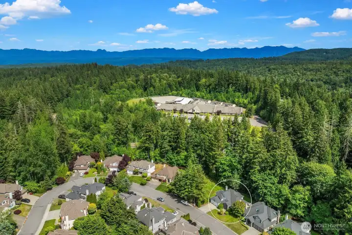 A sweeping aerial view showcases the home's prime location within the lush Klahanie community, surrounded by mature evergreens and just moments from the neighborhood's renowned amenities, trails, and open green spaces.