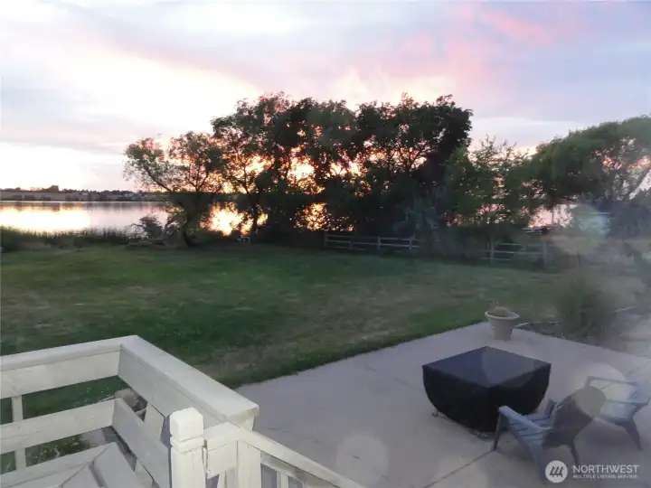 View of sunset from main deck and patio with fire table.