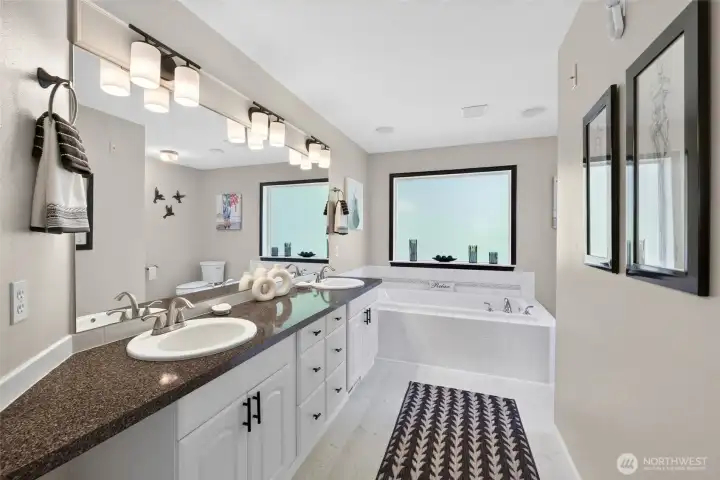 Refreshed attached primary bath with vinyl plank flooring, dual vanities, soaking tub and separate shower Refreshed attached primary bath with vinyl plank flooring, dual vanities, soaking tub and separate shower
