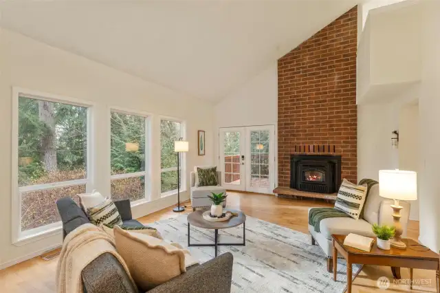 Formal living room features a dramatic floor to ceiling brick hearth, and French doors leading to the deck.