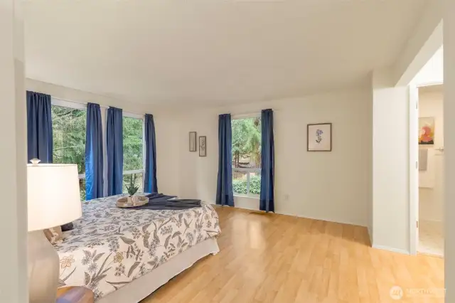 Upper level primary bedroom boasts a private bath, walk in closet, and a birds eye view of the tranquil grounds.