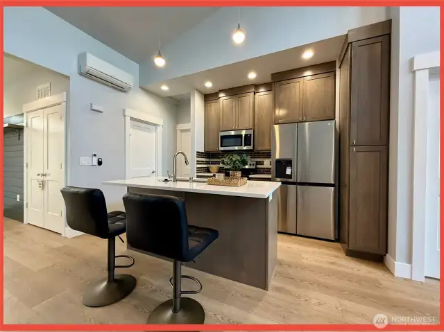 Spacious kitchen with Quartz countertops, glass backsplash, plenty of cabinetry, and island/breakfast bar.