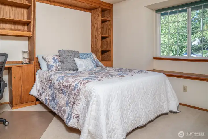 The second bedroom doubles as a stylish home office, with a built-in desk, custom wall storage, and a Murphy bed that tucks away for a clean, spacious look.