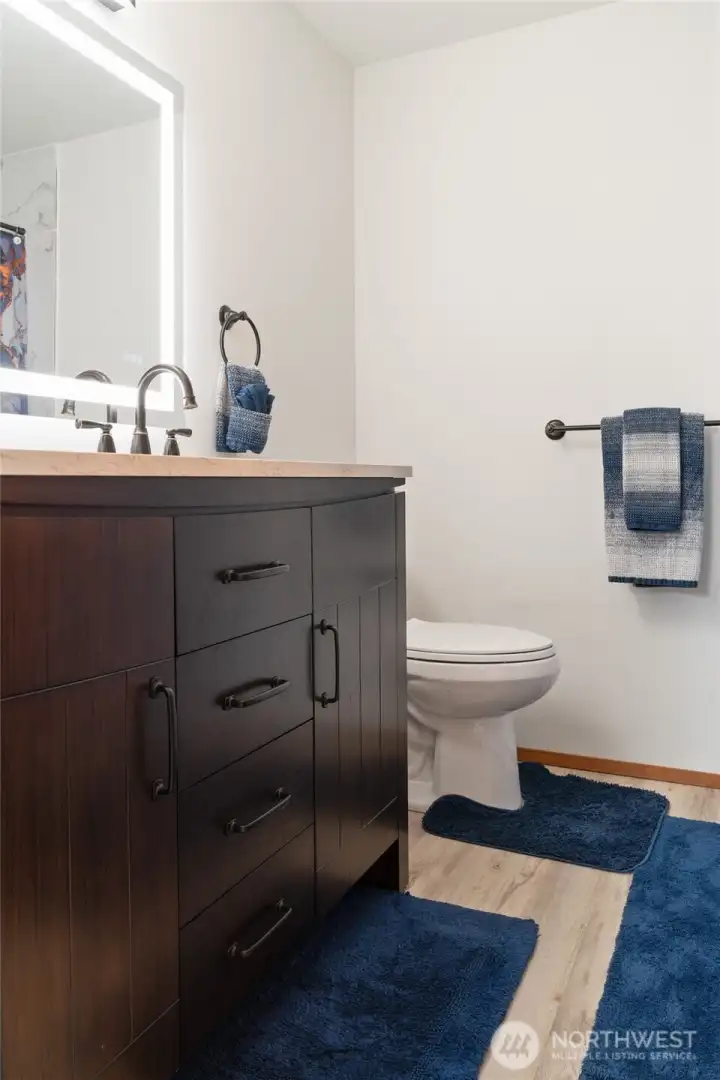 The newly remodeled upstairs bath features a stunning lighted vanity that makes the whole space glow.