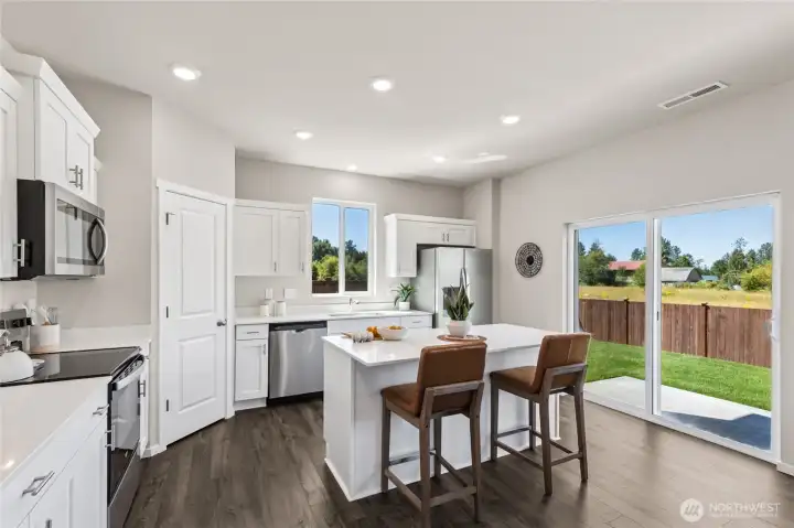 Large open kitchen with breakfast bar. Actual home is under construction and finishes, colors, and materials may vary. See site agent for details.