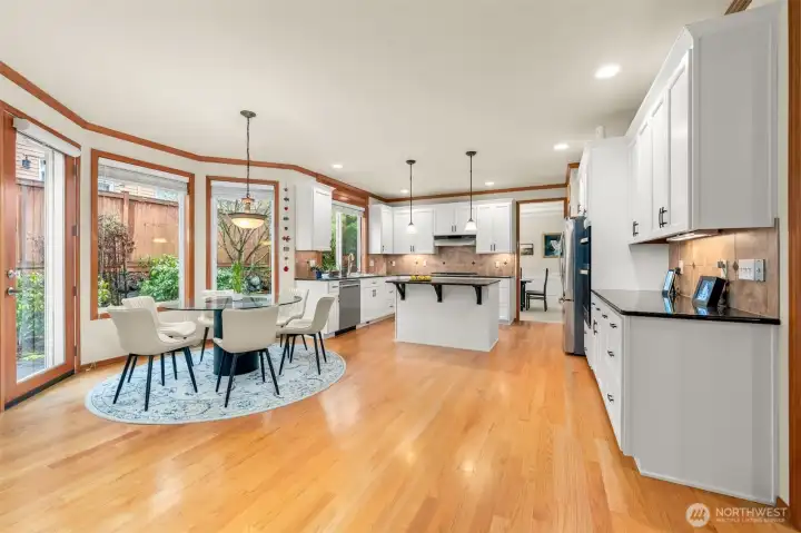 Chef's kitchen with a picture window, ample amount of quality cabinets, full backsplash, new stainless steel appliances, granite countertops, and island extends to a sun filled breakfast nook which opens to a sizable patio in fully fenced backyard with mature landscaping - a perfect place to relax and entertain