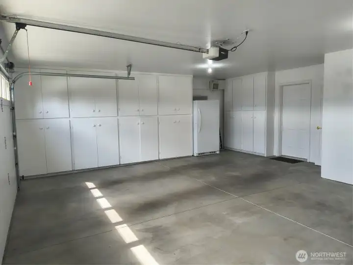 This oversize two-car garage boasts floor-to-ceiling built in storage and an included upright freezer!
