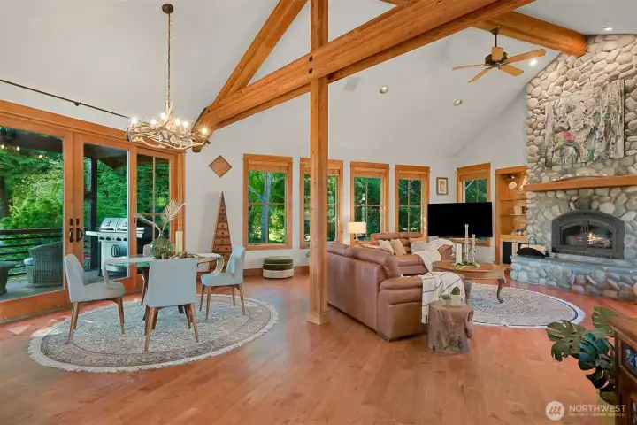 The great room features exquisite fir woodwork and bold architectural beams. A striking stone fireplace extends from floor to ceiling, creating a dramatic centerpiece.