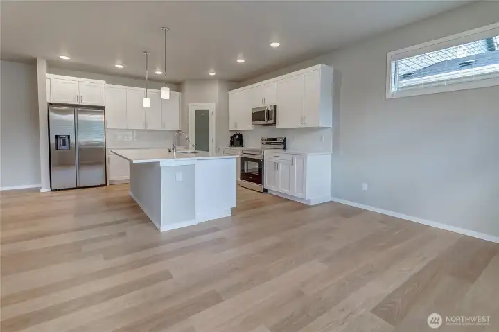 This stunning kitchen features an entertaining-size island with quartz counters, a full suite of stainless steel appliances, soft-close cabinetry with sleek pulls, a full-height tile backsplash, pendant lighting, an under-mount sink with garbage disposal, and a spacious walk-in pantry. Just off the kitchen, a large sunlit nook offers the perfect setting for everyday dining and family gatherings.