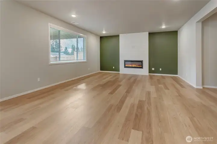 This spacious family room features oversized windows that fill the space with natural light, 1/2" laminate flooring throughout the main level, and a sleek modern linear fireplace for added warmth and style. Its open layout and generous size make it perfect for everyday living and effortless entertaining.
