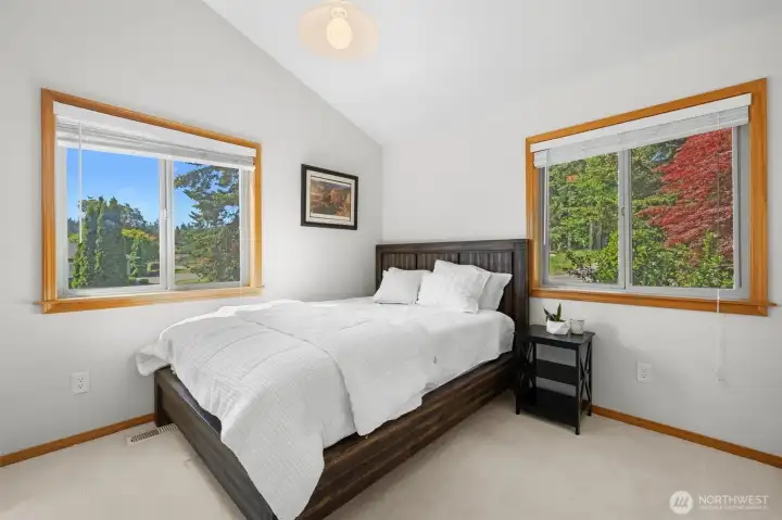 Peaceful bedroom filled with natural light and views of the mature landscaping.